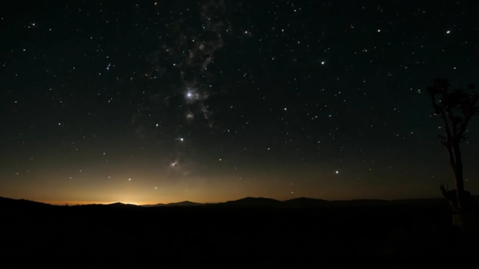 Céu noturno estrelado sobre uma paisagem escura e silenciosa