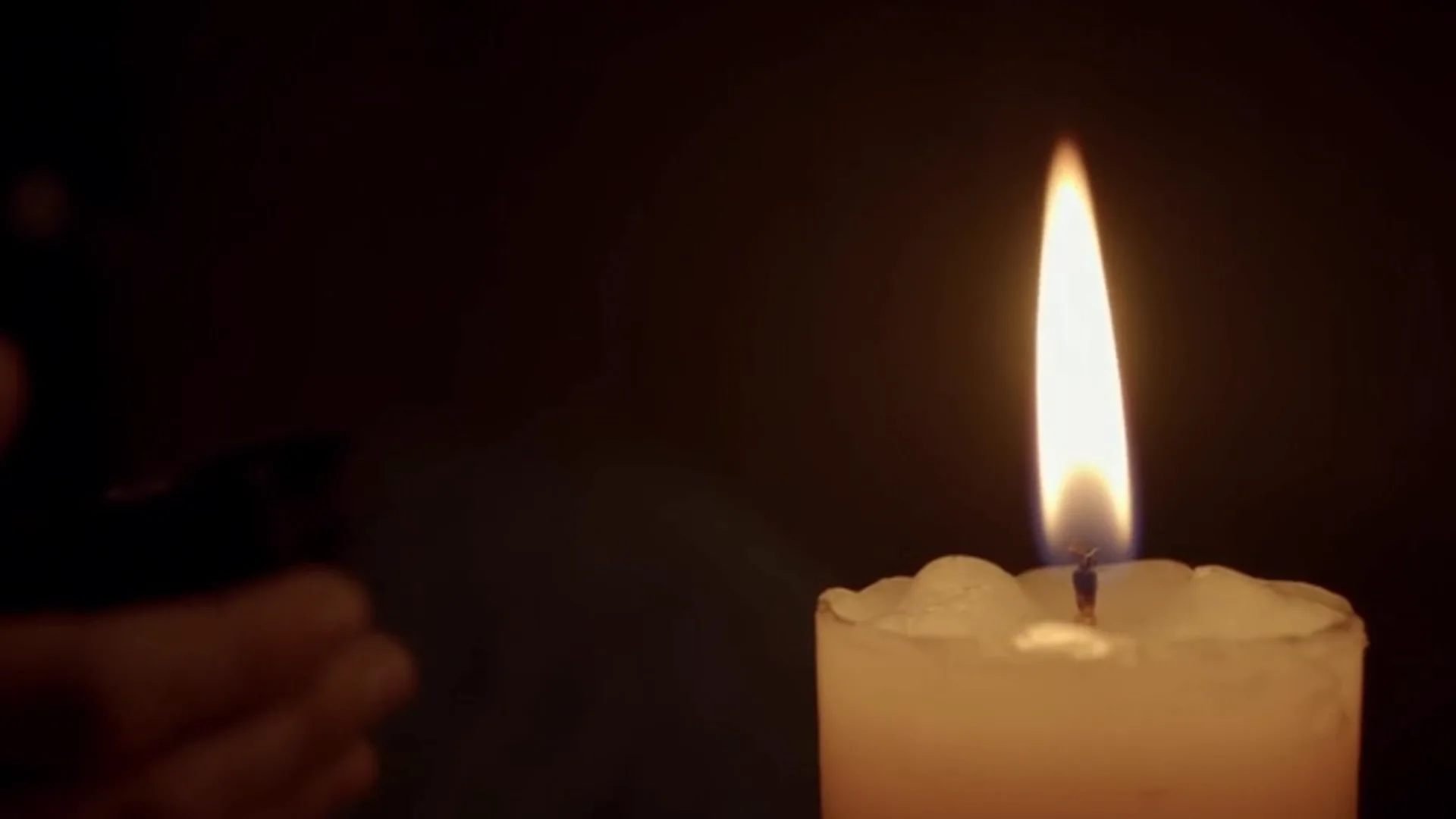 Uma única vela acesa refletindo luz suave na escuridão