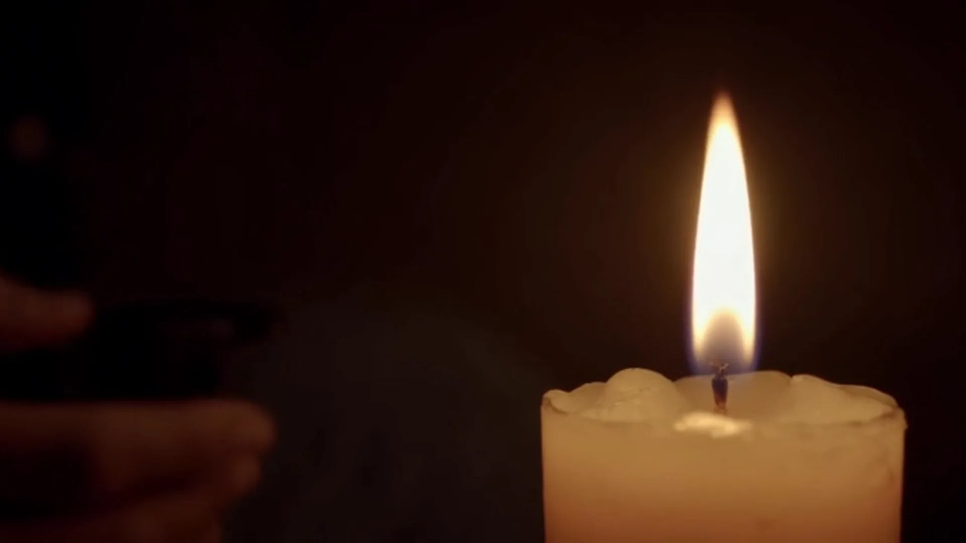 Uma vela acesa em um quarto escuro à noite