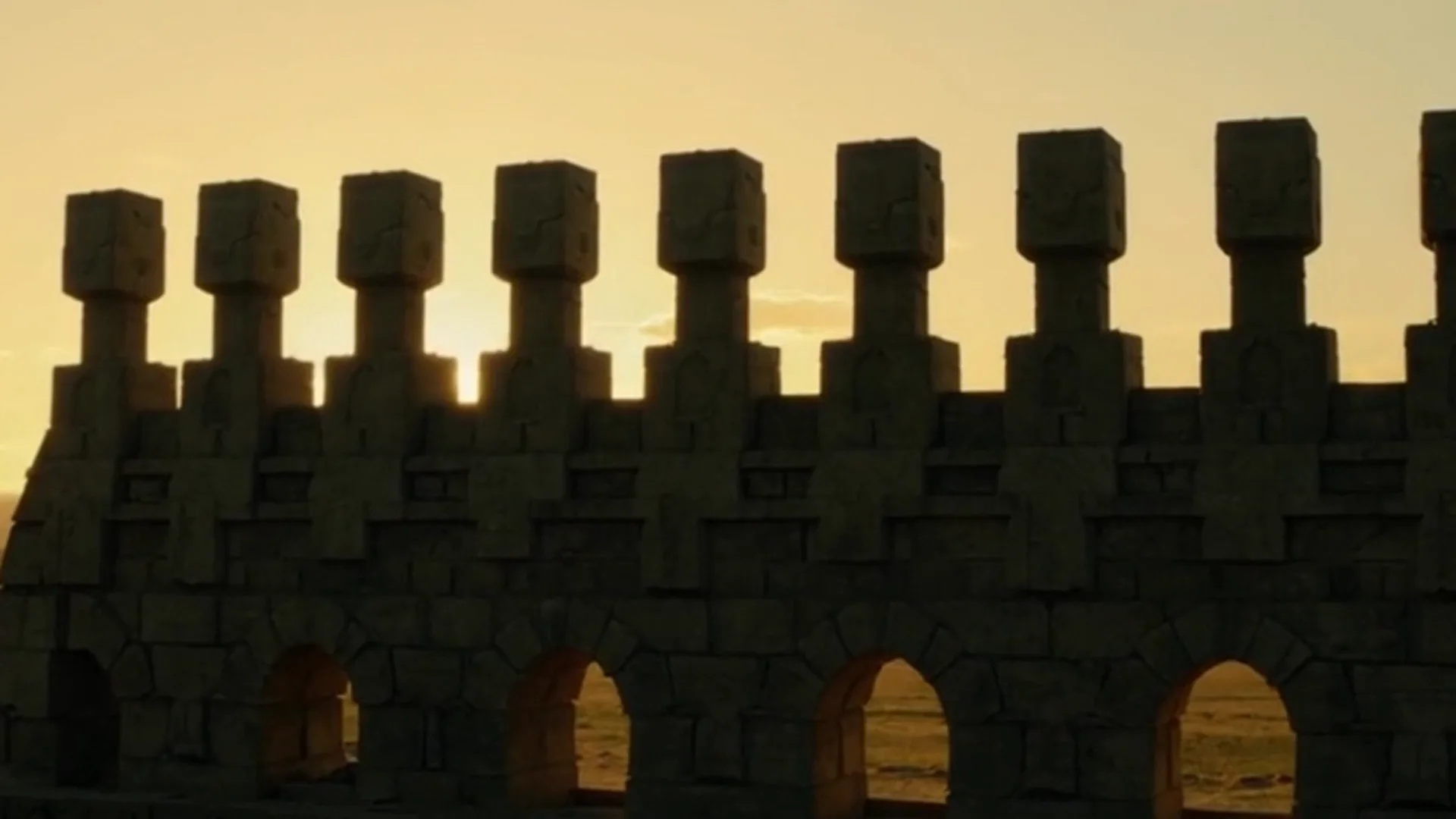 Uma muralha silhuetada contra um pôr do sol dourado, firme e serena
